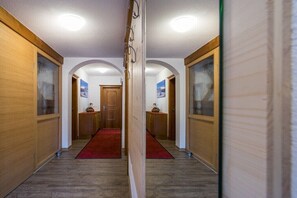 Ein Korridor mit Holzwänden, einem roten Teppich und einer Tür am Ende.