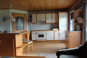 Una cucina compatta con mobili in legno, un'area pranzo con una sedia e un soffitto in legno.