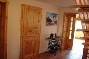 Eine Holztür, ein Tisch mit einer Nähmaschine und ein Gemälde an der Wand.