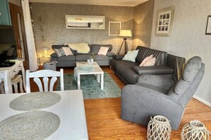 Ein Wohnzimmer mit zwei grauen Sofas, einem weißen Couchtisch und einem Fernseher-Schrank.