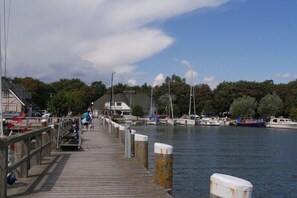 A wooden pier extending into calm water, with boats docked nearby and a building with a sign in the background. - Holiday apartment with 1 bedroom (Zingst)
