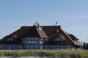 A traditional building with a steeply pitched roof, multiple chimneys, and a symmetrical facade with large windows. - Holiday apartment with 1 bedroom (Zingst)