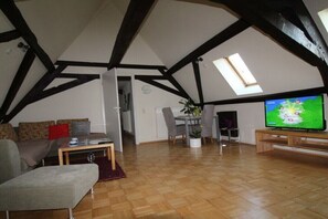A loft-style living room with exposed beams, a television, a dining area, and a skylight. - Holiday home with 4 bedrooms (Brachttal-Schlierbach)