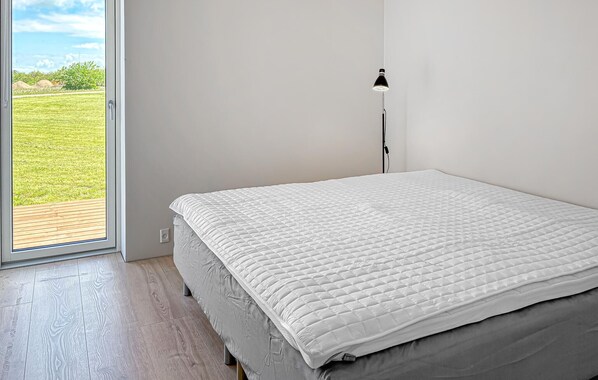 A bedroom with a bed, a window, and a floor lamp.