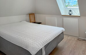 A bedroom with a bed, a window with a view, a radiator, and a chair.