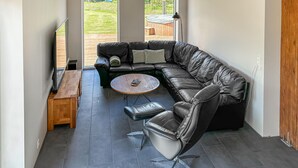 A modern living room with a sectional sofa, a round coffee table, a leather armchair, and a wooden side table. - Awesome home in Spøttrup with WiFi (Spøttrup)