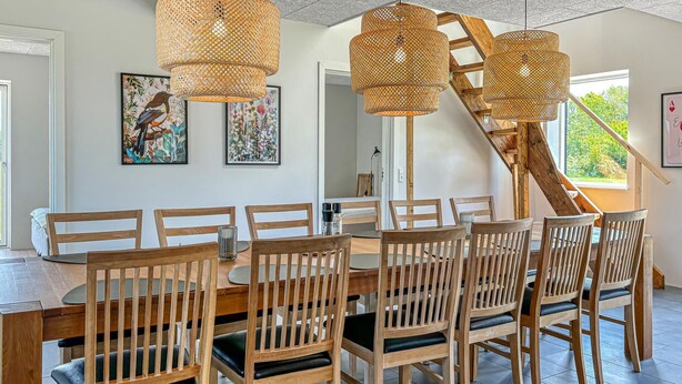 A dining area with a round table and wooden chairs, a staircase, and two framed artworks on the wall. - Awesome home in Spøttrup with WiFi (Spøttrup)