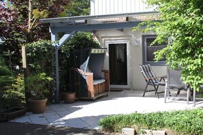 A patio with a covered seating area, a chair, and potted plants. - Holiday farmhouse with 2 bedrooms (Langenhorn)