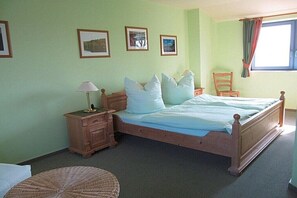 A bedroom with a wooden bed, a nightstand, a lamp, a chair, and framed pictures on the wall. - Holiday apartment in Waren with swimming pool (Waren)