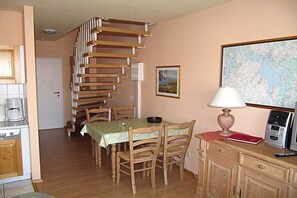 A dining area with a wooden table, chairs, a map on the wall, and a kitchen area with a stove and cabinets. - Holiday apartment in Waren with swimming pool (Waren)