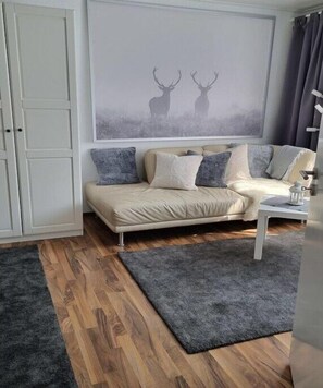 Ein Wohnzimmer mit einer Couch, einem Couchtisch, einem Teppich und einem Bild von Hirschen an der Wand.