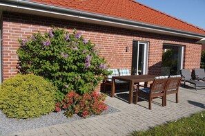 Ein Backsteinhaus mit Terrasse, Tisch und Stühlen.
