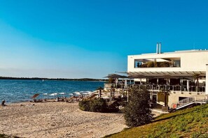 A modern building with a terrace overlooking a beach and the sea. - Holiday apartment Lillehus (Leipzig)