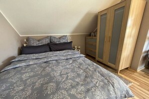 A bedroom with a bed, a wardrobe, and a nightstand. - Holiday apartment Lillehus (Leipzig)