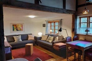 A cozy living room with a sofa set, a dining table, and a lamp. - Cozy thatched cottage (Klocksdorf)