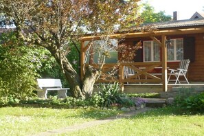 Eine Holzhütte mit Veranda, einer Bank und einem Tisch.