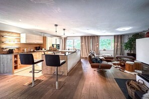 Eine moderne Küche mit Holdschränken, einer Kochinsel und Barhocker.