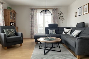 Ein Wohnzimmer mit grauem Sofa, Sesseln und einem runden Couchtisch.