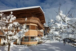 Ein traditionelles Chalet mit verschneietem Dach und einem Balkon.