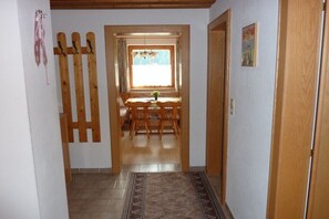 Ein Flur, der zu einem Essbereich mit Fenster, Holzmöbeln und einer Tür führt.