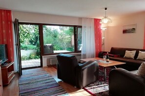 A living room with a sofa, chairs, a coffee table, a TV, and a large window with a view of greenery. - in the Allgäu region, the Kleinert family (Argenbuehl-Eglofs)