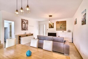 A modern living room with a sofa, dining table, and pendant lights.