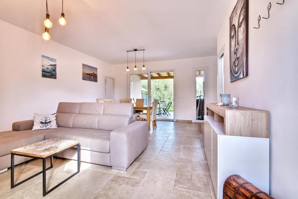 A modern living room with a sofa, a coffee table, and a dining area with chairs.