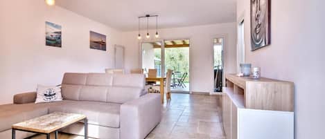 A modern living room with a sofa, a coffee table, and a dining area with chairs.