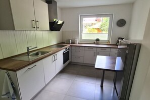 Eine kleine Küche mit Spüle, Herd und Fenster mit Jalousien.