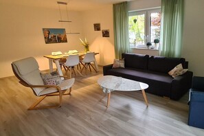 Ein modernes Wohnzimmer mit Sofa, Sesseln, einem Couchtisch und einem Essbereich.