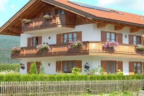 A two-story building with wooden balconies, flower boxes, and a white facade. - Holiday apartment in Krün with Wi-Fi (Krün)