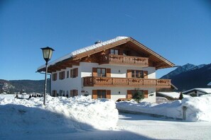 Ein mehrstöckiges Gebäude mit einem hölzernen Balkon, umgeben von Schnee.