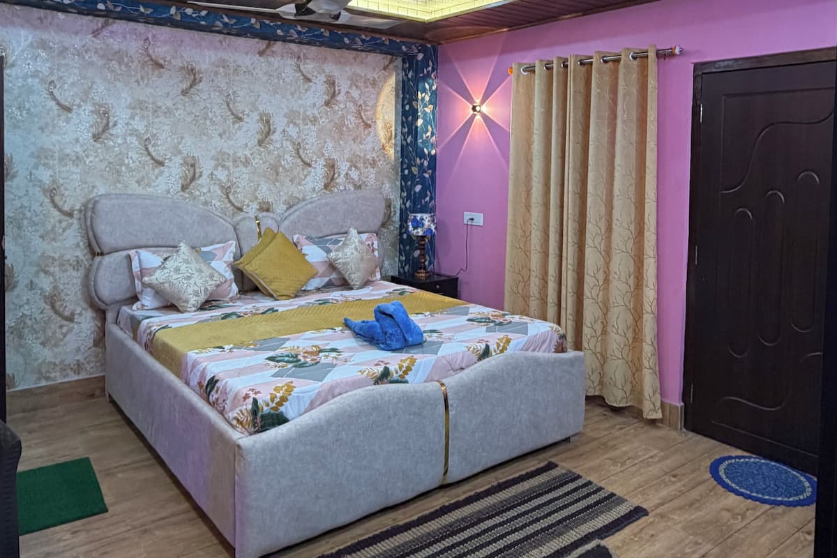 A bedroom with a bed, a ceiling fan, a wall-mounted light, and a door.