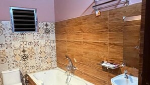 A bathroom with a freestanding bathtub, a sink, and a toilet. - Dev murti eco resort  (Mal)