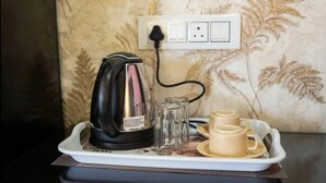 A kettle on a tray with two cups and three glasses, connected to a power outlet. - Dev murti eco resort  (Mal)