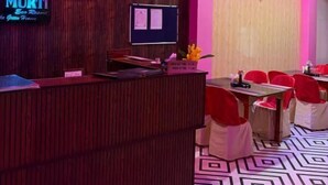 A reception area with a wooden reception desk, a flat-screen TV, and a wall-mounted sign. - Dev murti eco resort  (Mal)