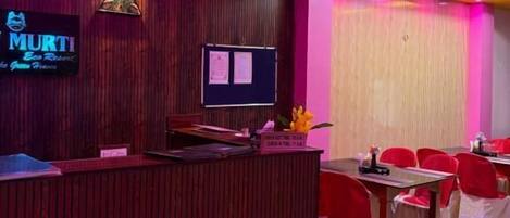 A reception area with a wooden reception desk, a flat-screen TV, and a wall-mounted sign.