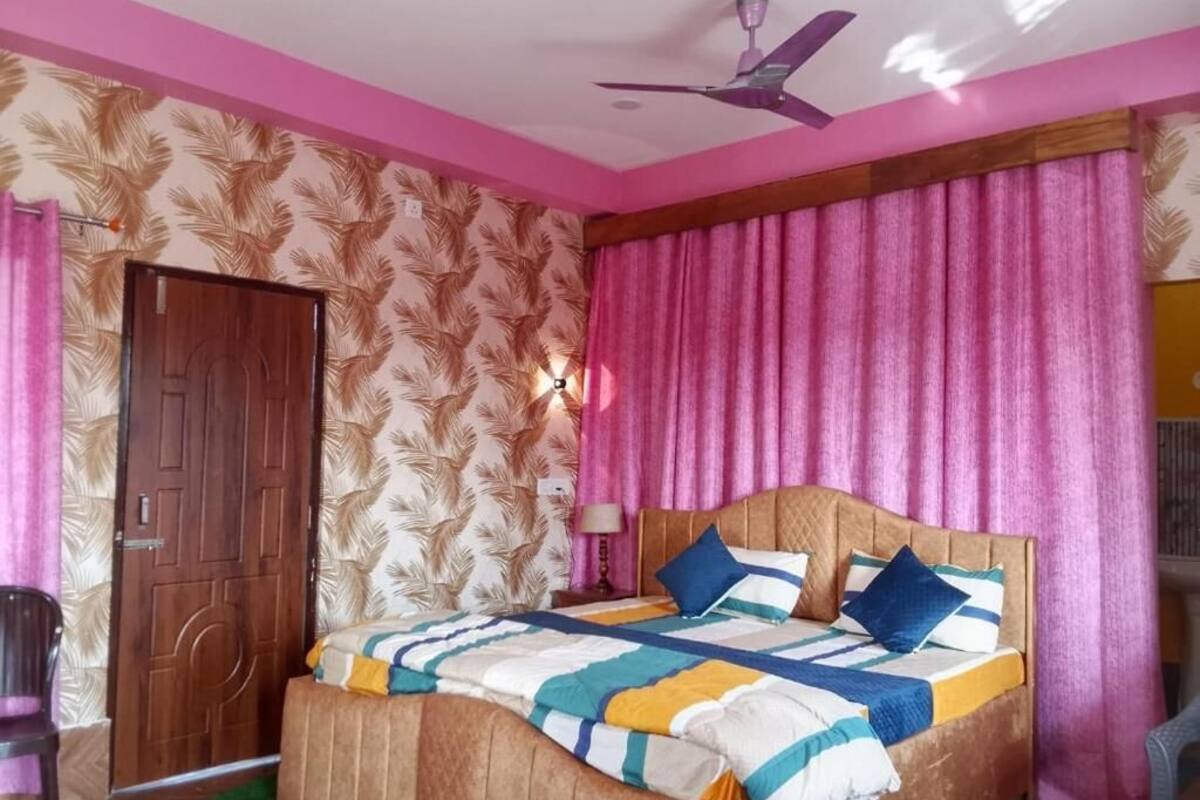 A bedroom with a bed, a ceiling fan, a door, and patterned wallpaper.