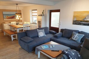 A living room with a sofa, a coffee table, and a dining area with a table and chairs. - Anchorage time pasture field (Kappeln)