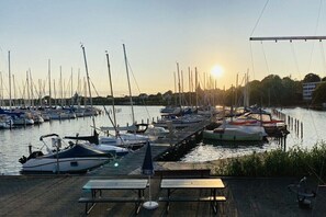Ein Yachthafen mit vertäuten Booten, ein hölzerner Steg und ein Sonnenuntergang im Hintergrund.