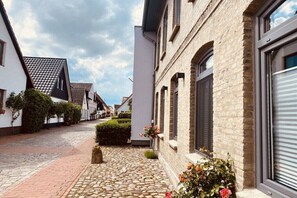 Eine enge Straße mit Kopfsteinpflaster, weiße Gebäude mit Backsteinfassaden und einem klaren Himmel.