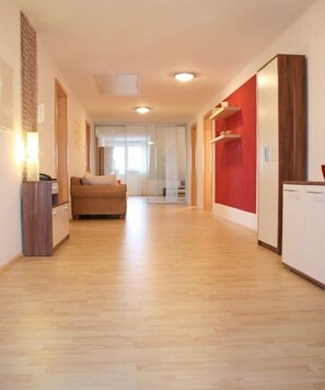 Ein geräumiger Flur mit Holzboden, einer Couch, einem Schrank und einer roten Akzentwand.