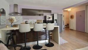 Eine moderne Küche mit einer zentralen Kochinsel, Barhocker, Backofen und Kühlschrank.