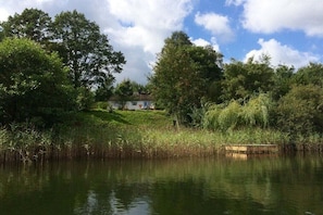 Ein Haus an einem ruhigen See, umgeben von üppigem Grün.