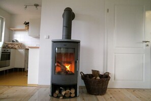 Eine moderne Küche mit Kaminofen, Holzkorb und einer weißen Tür.
