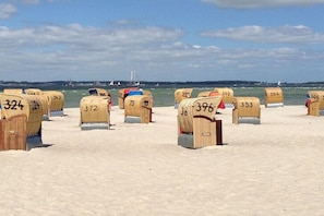 Beach huts numbered 324 to 398 on a sandy beach with a view of the sea and sailboats in the distance. - Holiday apartment in Laboe with swimming pool (Laboe)