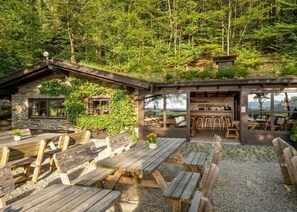 Eine rustikale Holzhütte mit Steinfassade, einer Holzterrasse und einem Sitzbereich im Freien.