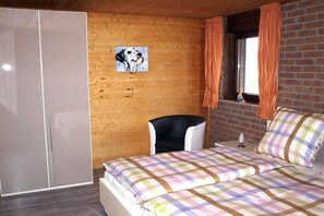 A bedroom with a bed, a chair, a wardrobe, a window with curtains, and a painting on the wall. - Holiday apartment with 3 bedrooms (Kevelaer)