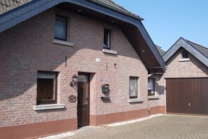 A brick building with a brown door, windows, and a garage door. - Holiday apartment with 3 bedrooms (Kevelaer)