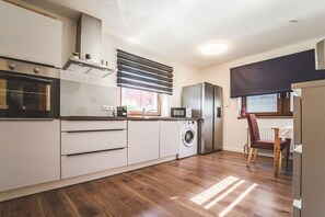Eine moderne Küche mit Waschmaschine, Kühlschrank und Essbereich mit einem Stuhl.